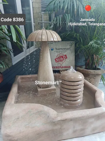 Another view of the stone mushroom fountain, showing the water cascading from the mushroom cap into the large basin below.