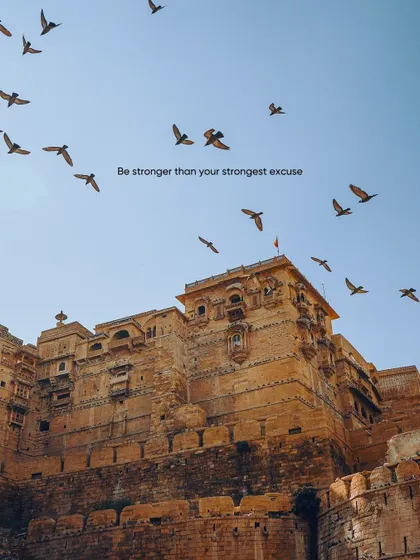 The majestic Jaisalmer Fort with a flock of birds taking flight. This shot captures the grandeur and life of the "Golden City."