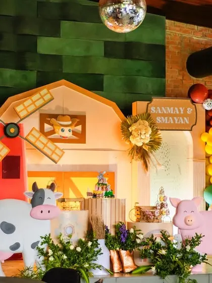 The full view of the barnyard stage, complete with a windmill, a friendly cow, and a happy pig. The lighting and green backdrop create a warm and rustic atmosphere inside the venue.