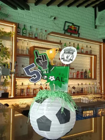Even the bar area gets a sporty makeover with this custom centerpiece featuring a soccer ball lantern and themed cutouts.