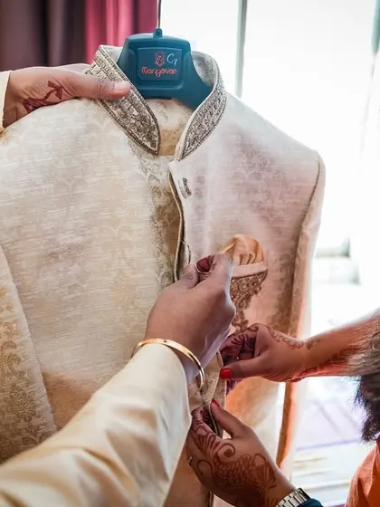 The details matter. This shot shows the groom's family helping him with the final touches on his wedding jacket, a moment of care and connection.