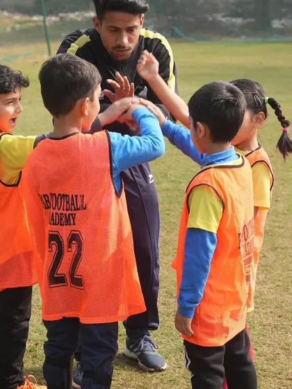 A coach and players in a huddle. We recognize the vital role coaches play in shaping the future of young athletes.
