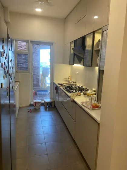 Another view of the compact parallel kitchen, showcasing the glossy, handleless cabinets that enhance the sense of space and make cleaning easy.