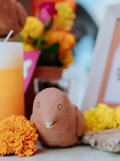 A close-up of a handcrafted clay bird, placed among fresh marigold flowers. These small, artisanal touches made the decor feel authentic and full of charm.