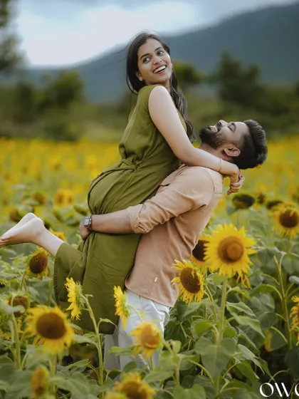The groom joyfully lifts his bride-to-be in a field of sunflowers, a classic and heartwarming pre-wedding photograph.