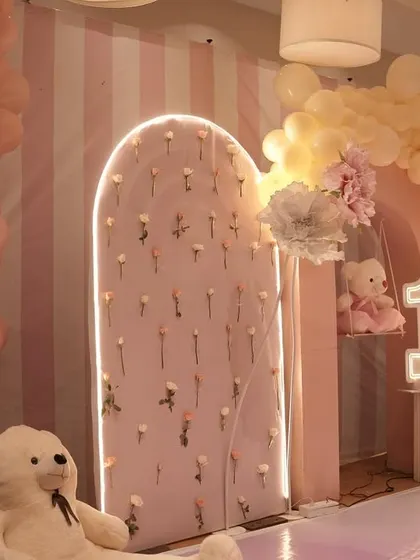 This pink floral decor features beautiful arched panels with inset flowers and a light-up number '1'. The large teddy bears add a soft and cuddly element to the design.