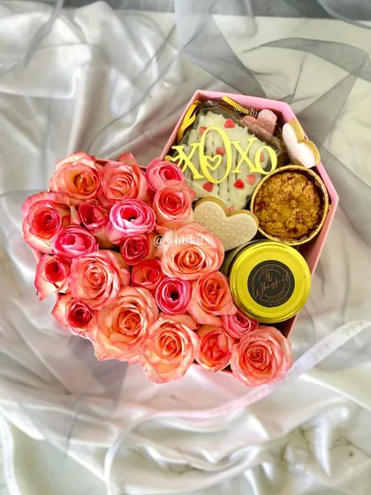 This heart-shaped gift box includes a brownie slab, cookies, a jarred dessert, and fresh roses, making it a complete and luxurious gift.