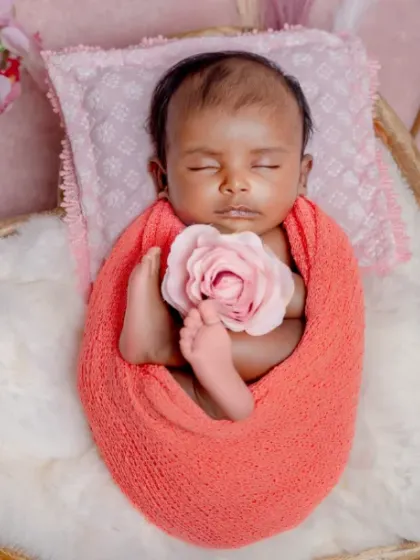As soft as a petal. This overhead shot shows a baby wrapped like a flower bud, holding a single pink rose.