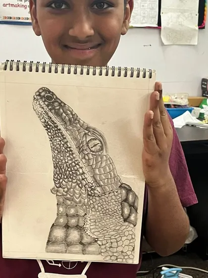 The proud result of a detailed animal study. This student has successfully captured the scaly texture and form of a crocodile's head, showcasing advanced pencil shading skills.