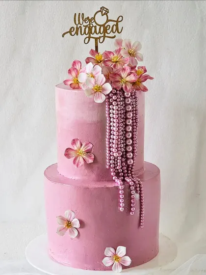 A gorgeous two-tiered pink engagement cake with cascading pearls and delicate sugar flowers. This design is the epitome of romance and elegance.
