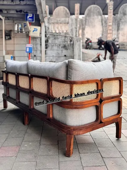 The back of this custom-made sofa showcases its beautiful craftsmanship, with a teak wood frame featuring multiple panels of hand-woven cane.