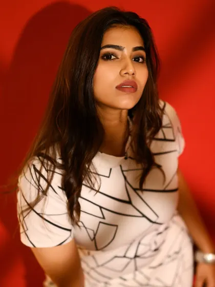 A close-up that highlights the model's expression against the bold red and the graphic lines of the dress.