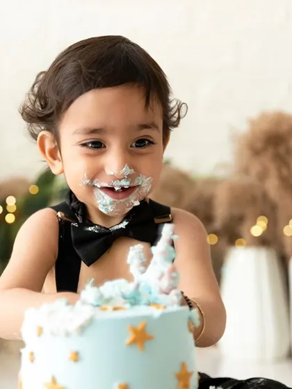 A joyful, messy smile from a first birthday boy enjoying his cake smash session.