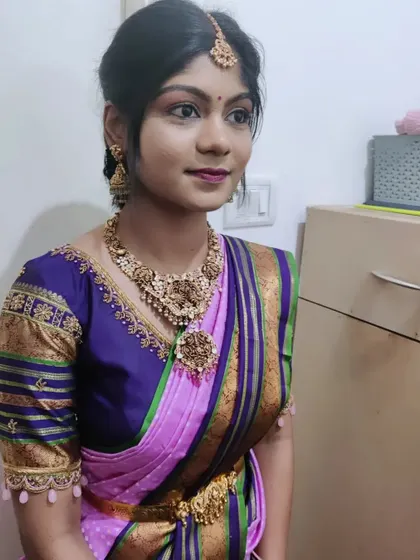 A simple yet elegant look for a non-bridal function. The makeup is clean and fresh, with a pop of color on the lips to complement her beautiful purple and pink saree.