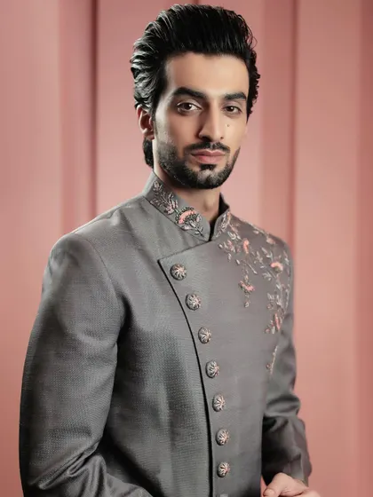 A close-up of our grey asymmetrical bandhgala. The unique button placement and delicate floral embroidery on the collar and shoulder make this a standout piece.