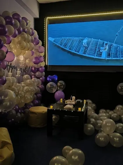 A serene moment during a birthday movie night, with the room decorated in shades of purple and white.