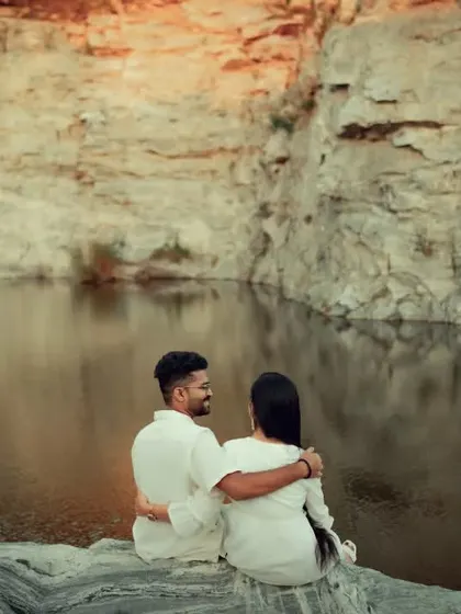 A serene pre-wedding shot of a couple enjoying a quiet moment by a quarry lake. The vast landscape and calm water provide a stunning and peaceful backdrop.