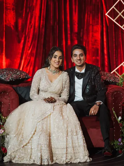 The couple posing at their Sangeet. The rich red velvet backdrop added a touch of classic glamour.