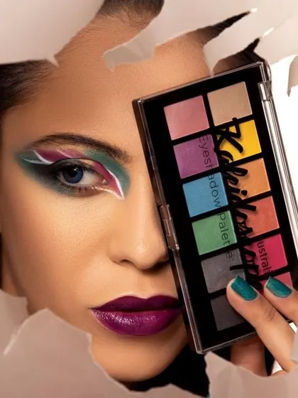A vibrant beauty photography shot featuring a model with creative eye makeup, holding an Australis eyeshadow palette. This shows my ability to work with makeup artists to create compelling visuals for cosmetics brands.