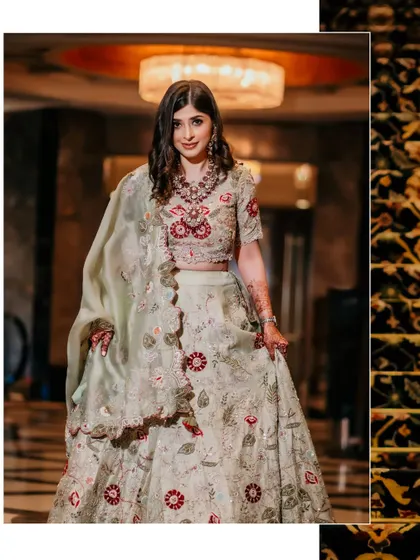 A solo portrait of the bride in her elegant pastel green lehenga, captured as she descends a beautifully carpeted staircase.