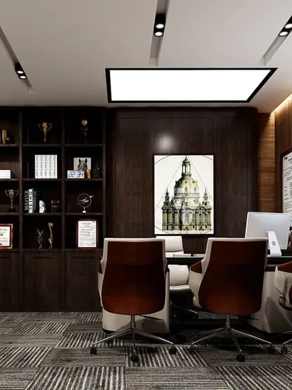 A view of the Managing Director's cabin, designed for both work and meetings. The space includes a large executive desk, comfortable visitor chairs, and extensive built-in shelving for awards and books, all framed by rich wood paneling.