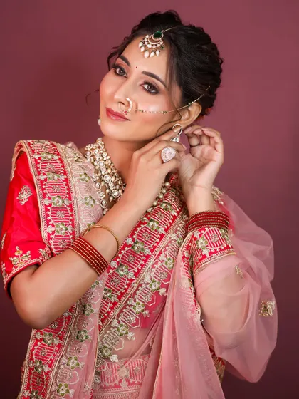 The model adjusting her earring, showing a close-up of the makeup and jewellery.