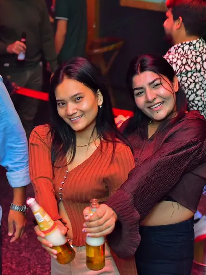 Two friends enjoying a drink and smiling for the camera. It's all about creating a relaxed and fun social atmosphere.
