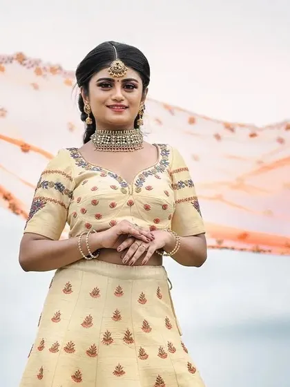 A client looking serene and beautiful in our cream-colored embroidered lehenga during an outdoor shoot.