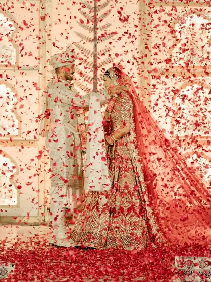 A shower of red petals during the varmala ceremony creates a dramatic and romantic effect, making the moment truly unforgettable.