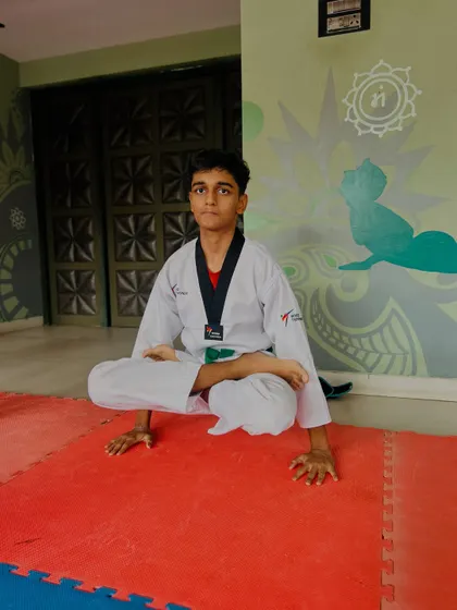 A student holds a difficult seated balance pose, showcasing his core strength and focus.