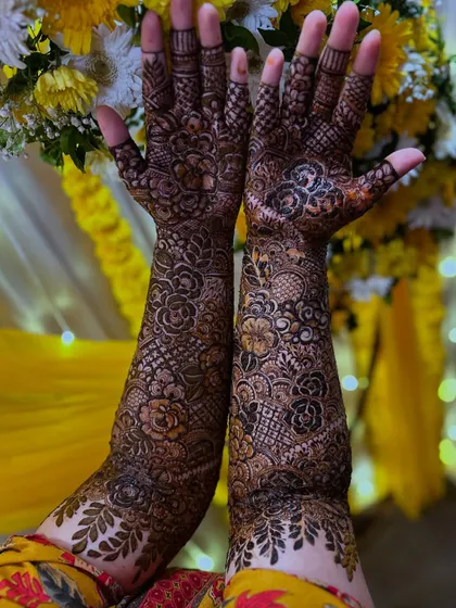 The bride's hands held up to showcase the complete floral design against a festive wedding backdrop.