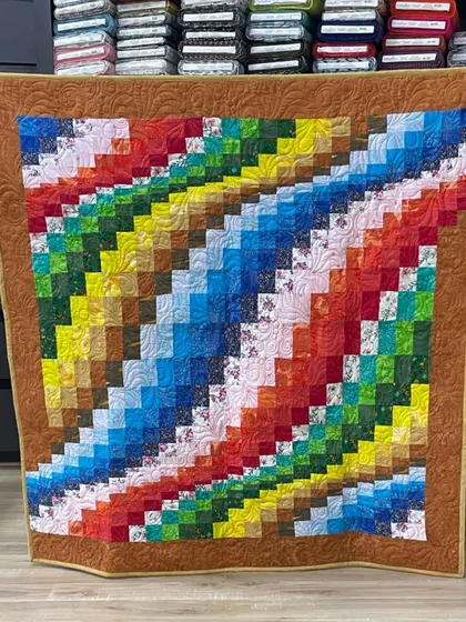 A colorful bargello-style quilt with a rainbow of colors arranged in a diagonal pattern.