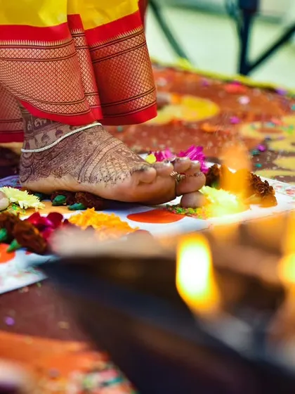 A detail shot of the Saptapadi ritual, where the bride's foot touches a mound of rice, marking one of the seven sacred steps around the holy fire.
