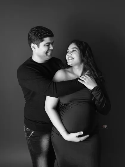 A joyful black and white portrait of an expecting couple. Their smiles and embrace tell a beautiful story of love and happiness.