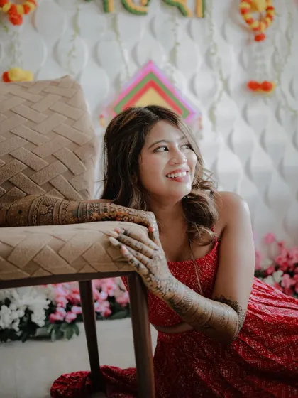 A lovely candid portrait of the bride looking away with a happy smile. This shot captures her natural joy and the beautiful details of her mehndi.