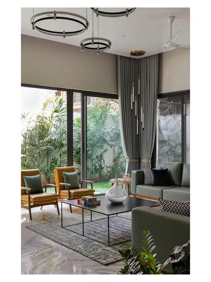 The living room of the "Solid | Void | Solid House" opens completely to a lush garden. The use of a neutral color palette with green accents blurs the line between inside and out.