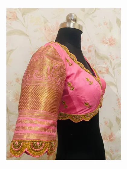 A pink bridal blouse with scalloped cutwork edges and delicate embroidery. The sleeves are made from the saree's gold brocade border.