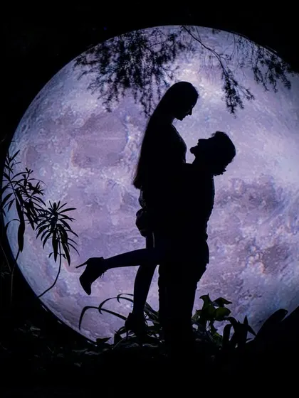 A romantic lift silhouetted against a purple-hued moon. This shot is full of drama and passion, creating a truly memorable and artistic pre-wedding photo.