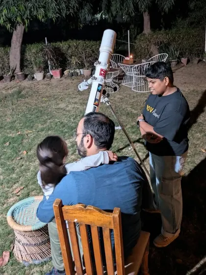 A father holds his child as they look through the telescope together, a shared moment of wonder.