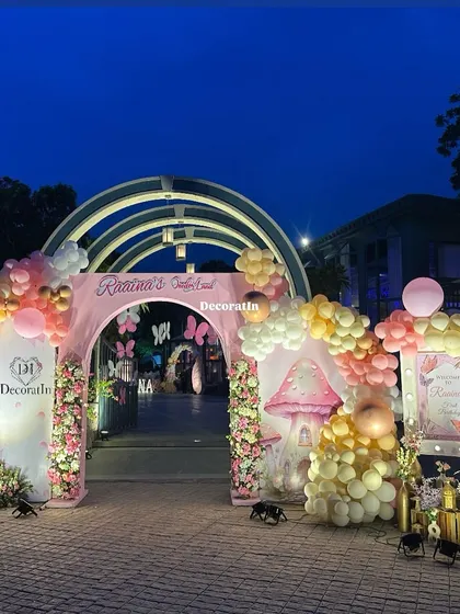 The full view of the grand entrance arch, showcasing the "Raaina's ONEderland" sign and the whimsical mushroom house prop.