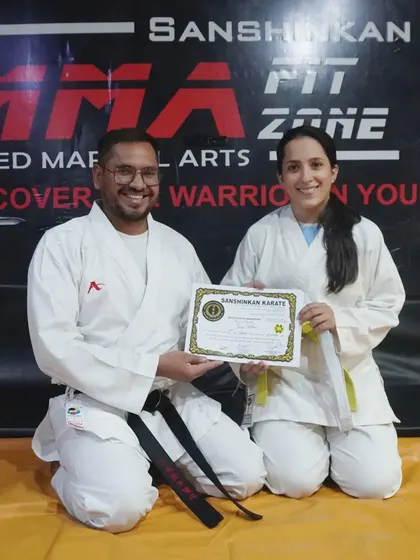 Another student proudly receives her certificate and new belt after a successful karate grading. Each belt represents a new level of skill and responsibility.
