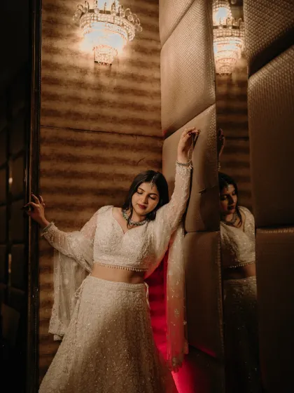 A glamorous bridal portrait. The bride's pose against a textured wall with dramatic lighting creates a chic and modern look.