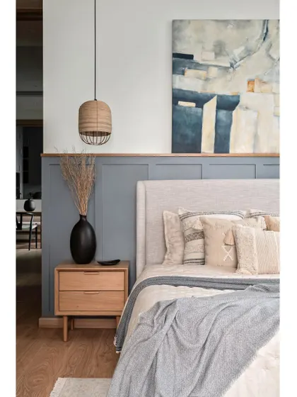 The master bedroom embraces simplicity with a curated color palette. MDF wainscoting painted in a tranquil grey graces half of the bed wall, while the other half remains pristine white, adorned with a captivating abstract artwork.