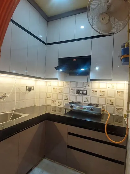 Another angle of the compact kitchen, highlighting the glossy white upper cabinets that help make the space feel brighter and larger.
