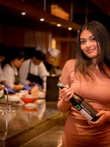A candid shot of a guest holding a bottle of wine, with the restaurant's open kitchen in the background. This type of photo adds context and a lifestyle feel to the event gallery.