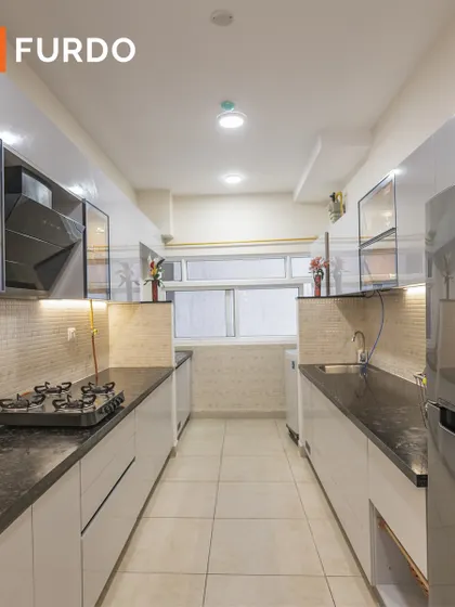 A sleek parallel kitchen with high-gloss white cabinets and black granite countertops. We maximized storage and functionality in this compact space with features like glass-front upper cabinets and under-cabinet lighting.