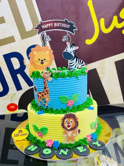 A colorful 2kg two-tiered jungle cake with a ribbed buttercream texture and cartoon animal toppers.