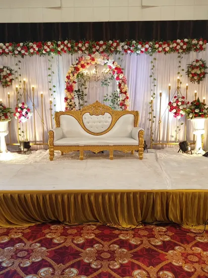 This is the kind of elegant stage setup I love creating for weddings and receptions. The combination of white and red flowers, a classic golden-white sofa, and warm candle lighting creates a timeless and grand look for your special day.