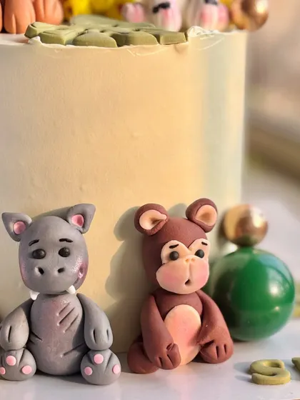 A close-up of the hand-molded fondant hippo and monkey from the jungle theme cake, showcasing their cute expressions.