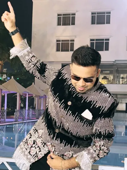 Pointing to the sky, feeling the energy in my elaborate designer jacket. The poolside setting adds to the glamorous vibe.